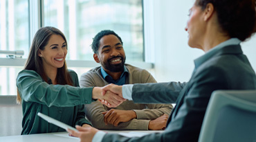 A couple shake the hand of a female insurance agent.